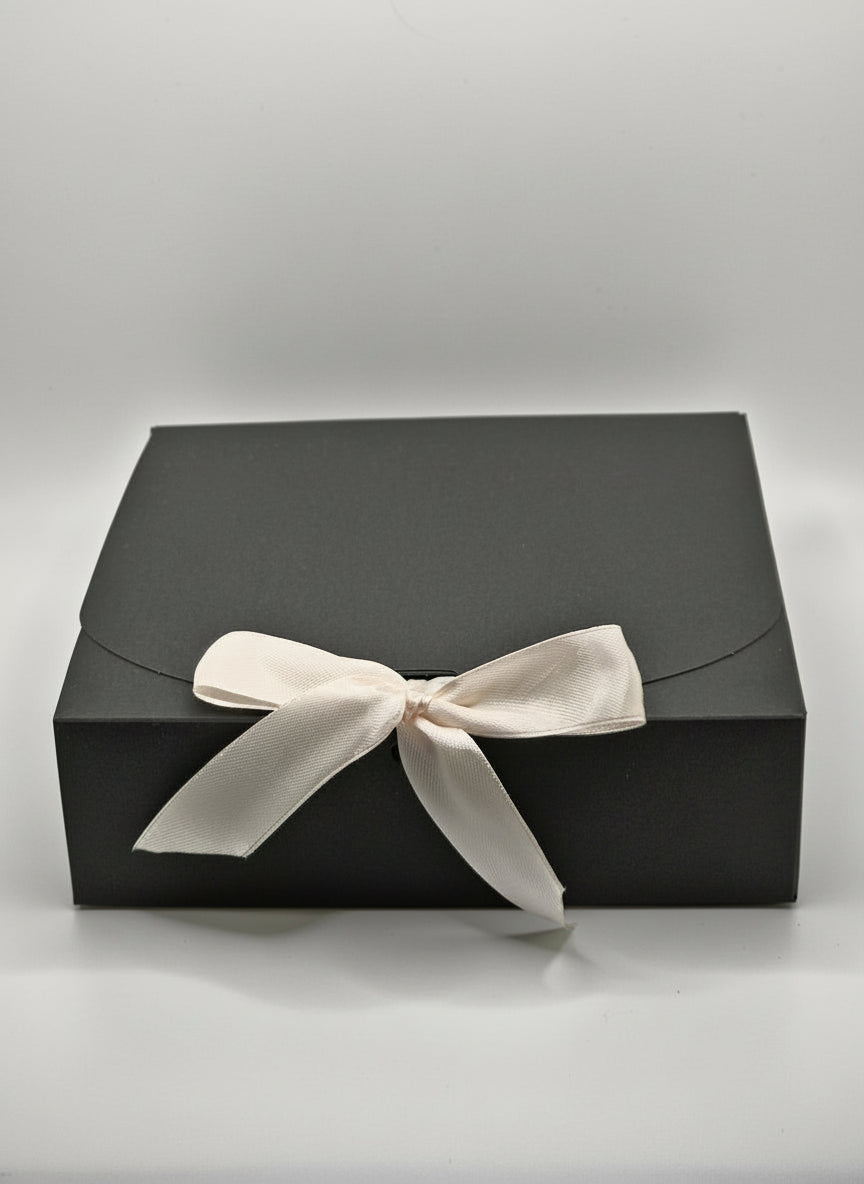 Black gift box with a white ribbon on a light gray background